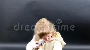 可爱的女孩梳头。 小女孩穿着冬天的衣服。 可爱的黑背景小女孩。